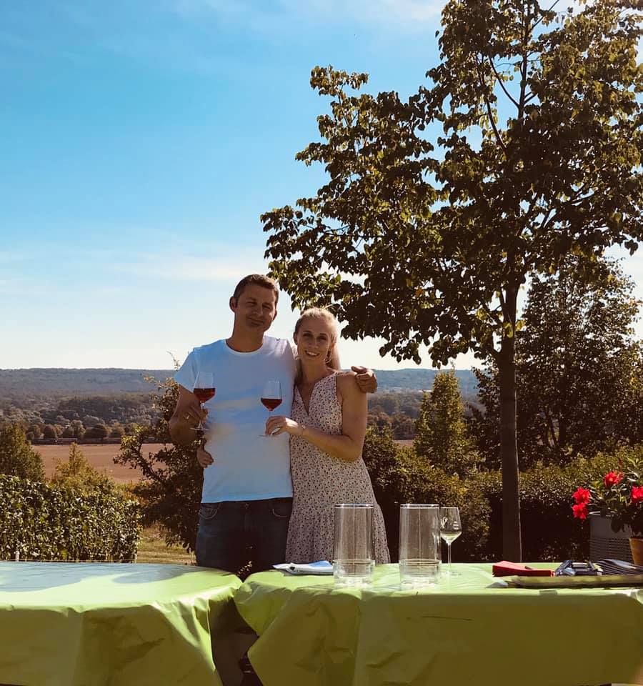 André Bug mit einer Flasche Wein vor dem Holzfass
